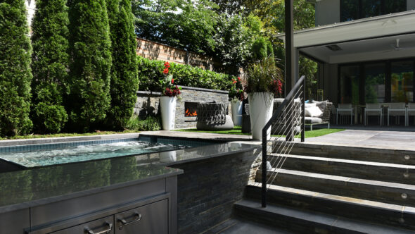 Standing in outdoor kitchen space looking toward Blade fireplace across the spa